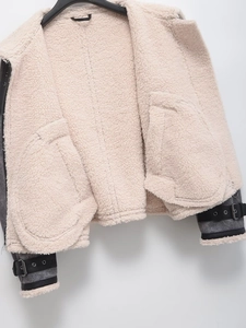 Detail of grey suede jacket featuring warm white sherpa lining and metal buckle sleeve straps