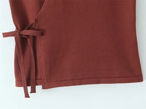 Detailed close-up of dark reddish-brown knit fabric showing elegant side tie-knot bow detail