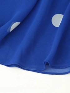 Détail du tissu bleu roi à pois blancs avec finitions soignées de l'ourlet de la robe