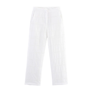 Dettaglio dei pantaloni bianchi a vita alta con intricati ricami traforati e trama a griglia