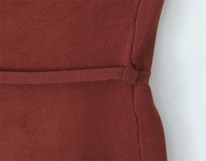 Macro view of the rust red knitted waist detail with matching integrated belt loops