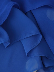 Détail macro du tissu mousseline à pois bleu marine avec des bords de volants superposés