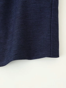 Gros plan sur la texture du tissu sergé bleu foncé et les coutures de l'ourlet du gilet