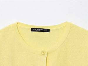 Detail view of yellow knit cardigan collar with ZEAL WOMAN brand label and fine textures