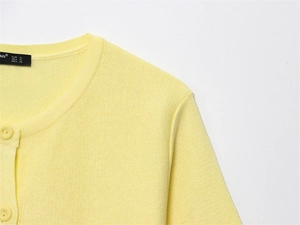 Close-up of light yellow knit cardigan featuring smooth round neck and tonal button detail