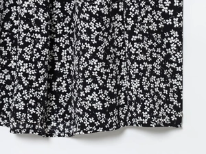 Detail of floral print fabric with black base and delicate white blossoms for summer dress