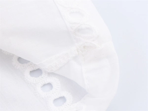 Dettaglio del ricamo traforato bianco e delle cuciture su una camicia casual in cotone
