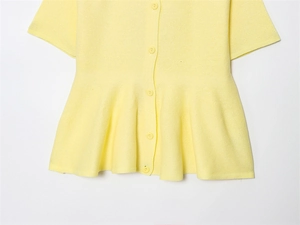Macro view of lemon yellow knit top featuring single-breasted buttons and peplum hem detail