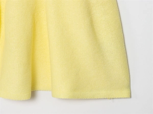 Close-up of yellow knit dress hem showing fine mesh texture and professional stitching