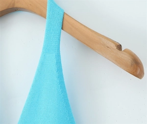 Close-up of sky blue knit halter top texture and strap detail on a wooden hanger
