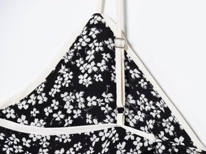Detail of floral dress with adjustable white straps and silver metal buckles