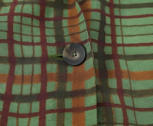 Macro view of green and brown plaid fabric texture with a premium faux horn button