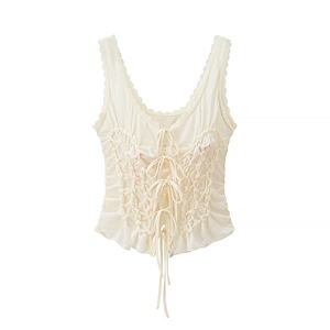 Close-up of smocking texture and bow tie details on a white lace-trimmed tank top