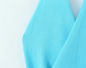 Macro shot of light blue knit vest showing detailed fabric texture and v-neck stitching