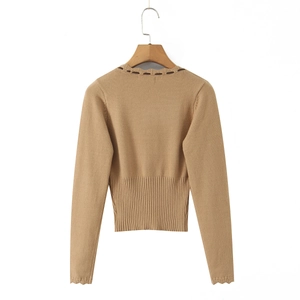 Dettaglio del top in maglia color cammello con bordi ondulati e vita a coste su gruccia