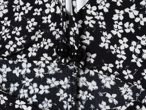 Close-up of black floral dress fabric with white daisy print and black bead details