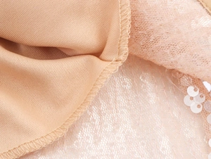 Gros plan sur le tissu en dentelle à paillettes beige d'une robe de soirée chic