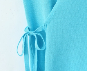 Detail shot of light blue knit top featuring side lace-up bow and fine texture