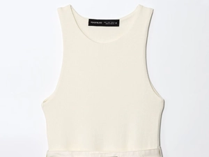 Detailed view of the woven neck label on a cream white ribbed knit sleeveless top