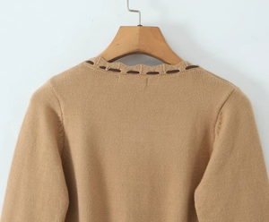 Dettaglio dello scollo a volant e nastro scuro su maglione in maglia color kaki