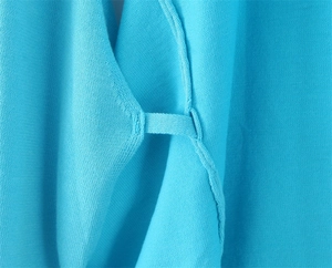 Detailed close-up of blue knitted fabric texture and precise stitching on the halter top