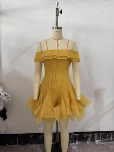 Détail d'une robe jaune à épaules dénudées avec volants et couches de mousseline