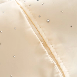 Macro view of cream satin fabric with sparkling silver rhinestones and fine stitching details