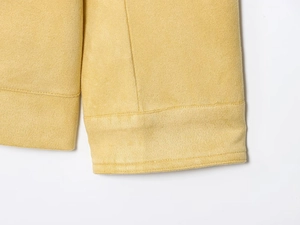 Detail shot of ribbed cuffs and soft brushed texture on a mustard yellow faux suede jacket