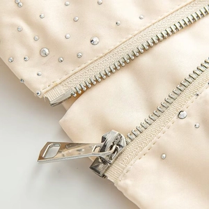 Detail of champagne satin jacket with silver rhinestones and metallic zipper