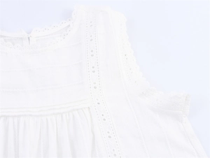 Close-up of white cotton top featuring intricate broderie anglaise and pleated details
