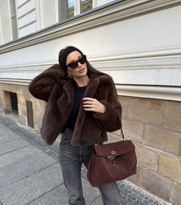 Detail einer dunkelbraunen Webpelzjacke kombiniert mit einer Wildleder-Umhängetasche