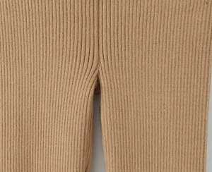Dettaglio dei pantaloni in maglia color cammello con trama a coste e cuciture