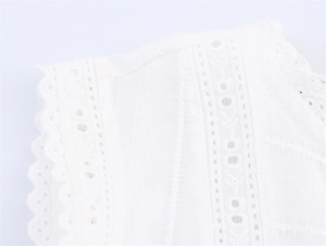Close-up of white top featuring delicate eyelet embroidery and scalloped lace edges