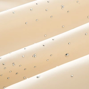 Macro detail of silver rhinestones on light beige fabric of this stylish bomber jacket