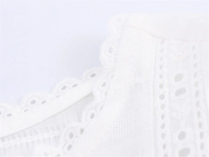 Detailed macro view of white cotton fabric with elegant eyelet embroidery and scalloped edges