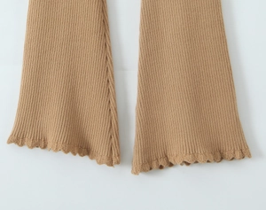 Dettaglio dei pantaloni in maglia color cammello con trama a coste e bordo a volant