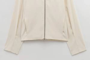 Detail of off-white zippered jacket showing smooth satin texture and silver metal zipper
