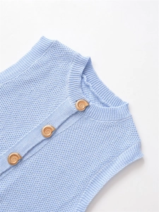 Detailed view of light blue knit vest with unique golden snail-shaped metal buttons