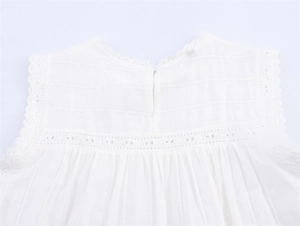 Detail view of white eyelet lace trim and button back on a breathable cotton top