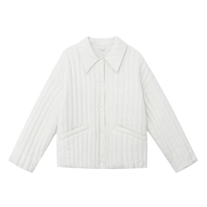 Detail of white quilted jacket featuring classic lapel collar and button closure