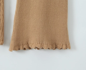 Dettaglio di maglia a coste color cammello con eleganti bordi a balze sui polsini
