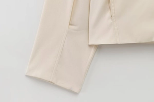 Detailed close-up of cream-colored jacket sleeve with high-quality twill texture and stitching