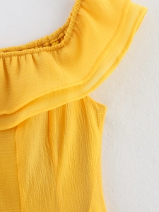 Détail de l'encolure à volants et texture plissée sur une robe jaune vif à épaules nues