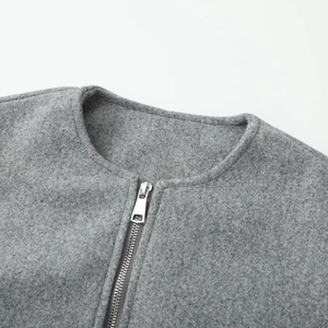 Close-up of grey textured fabric jacket with round neckline and silver metal zipper