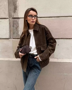 Close-up of a vintage brown suede bomber jacket with large utility pockets and lapel collar
