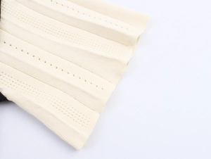 Gros plan détaillé du tissu en maille crème avec côtes verticales et motifs pointelle
