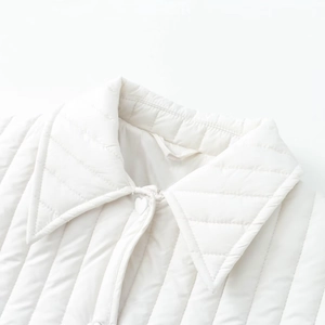 Detailed macro view of white quilted cotton jacket with pointed collar and diamond pattern