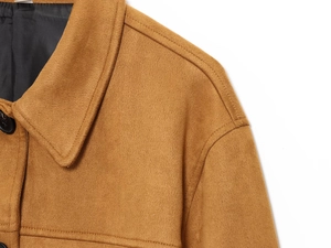 Détail de la veste en laine camel montrant le revers, le bouton noir et la couture