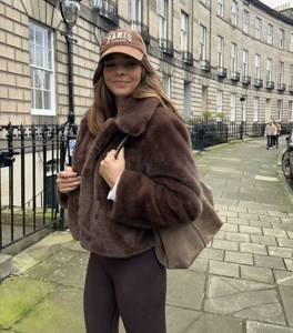 Streetstyle-Aufnahme einer dunkelbraunen Webpelzjacke mit passender Wildleder-Schultertasche