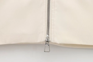 Close-up of the smooth silver metal zipper and neat stitching on this beige jacket